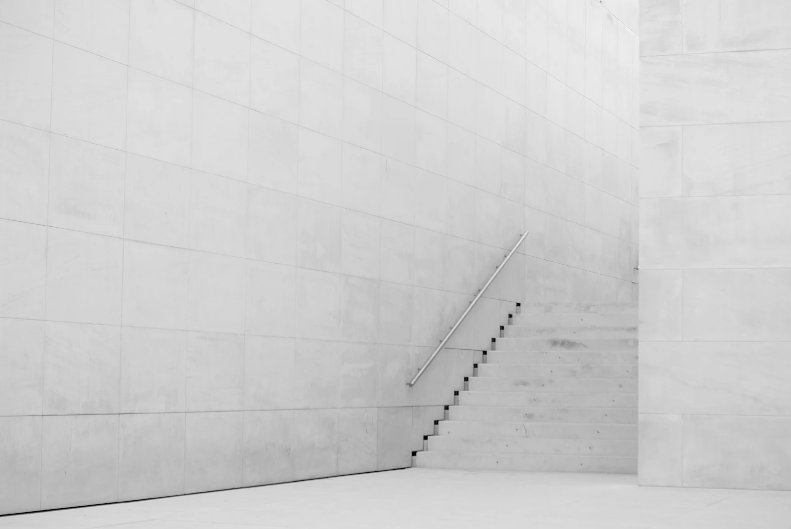A flight of white concrete stairs cut by a hard diagonal shadow.